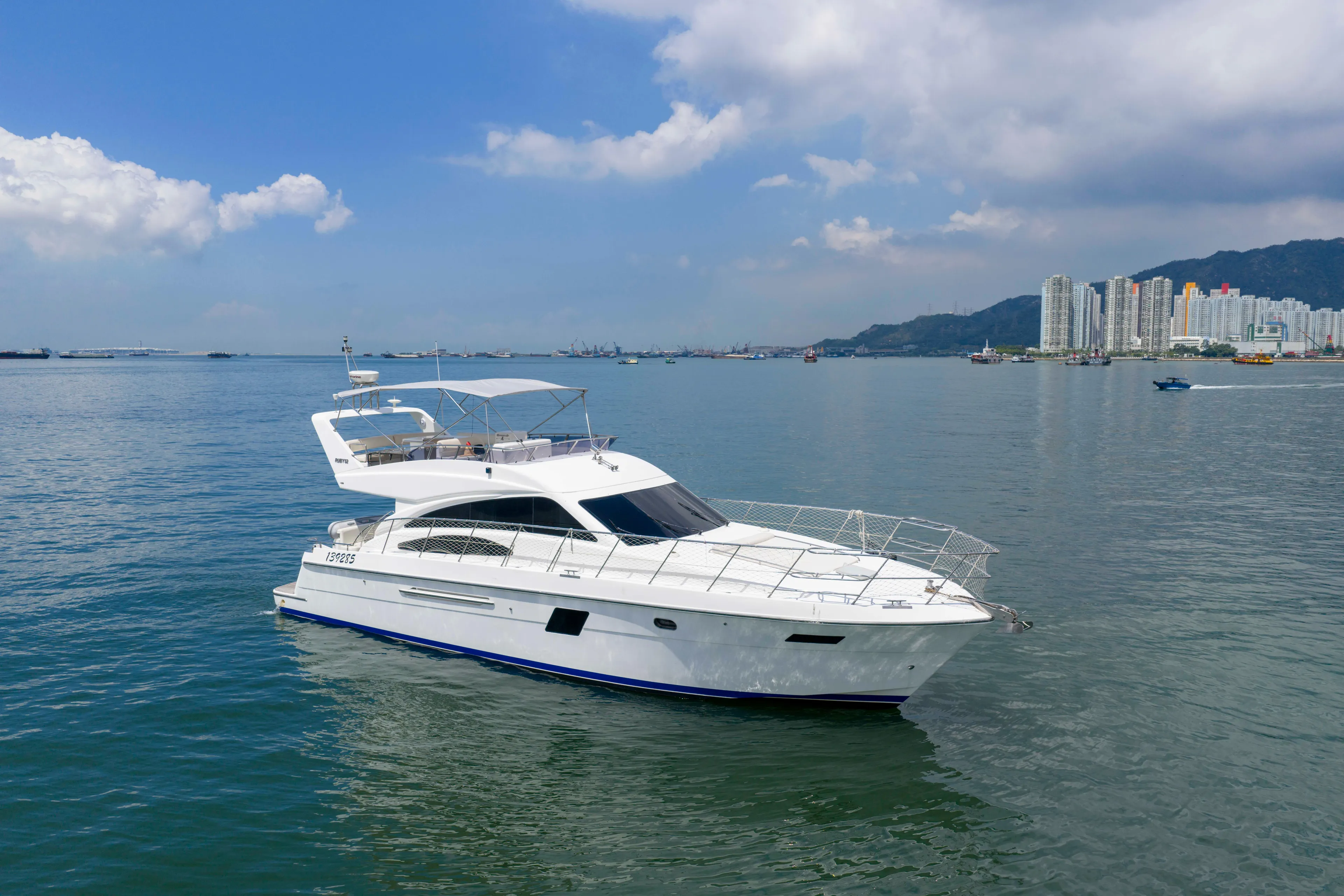 Luxurious 2009 Ruby 52 yacht cruising on calm waters near a city skyline.