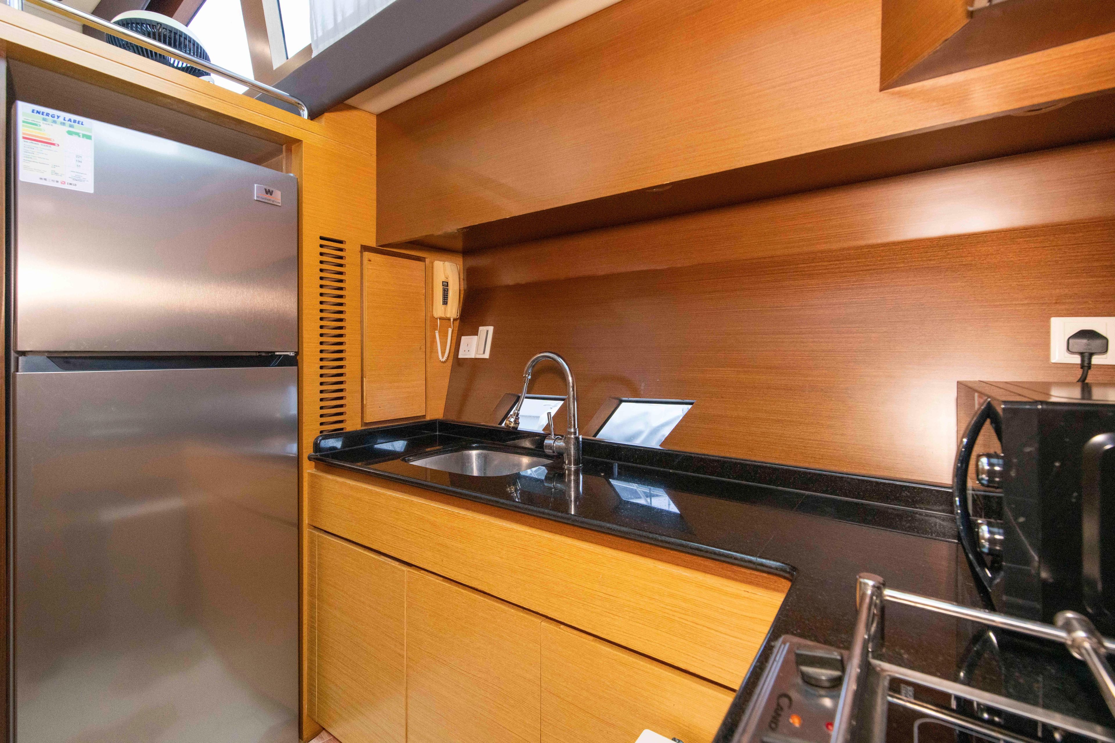 Modern yacht kitchen with stainless steel appliances, wooden cabinetry, and sleek black countertops. Ruby 52, 2009.