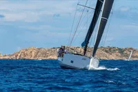 Sailing yacht Solaris 58, 2016 model, navigating blue waters near rocky coastline.