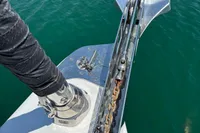 Bow of 2016 Solaris 58 yacht with anchor chain over clear water.