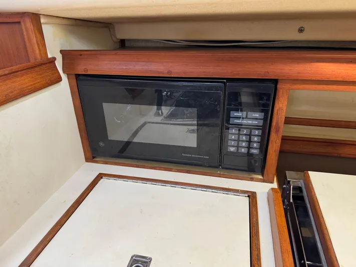 Otter II Yacht Photos Pics Microwave in 1999 Island Packet 45 yacht kitchen, featuring wood trim and compact design.