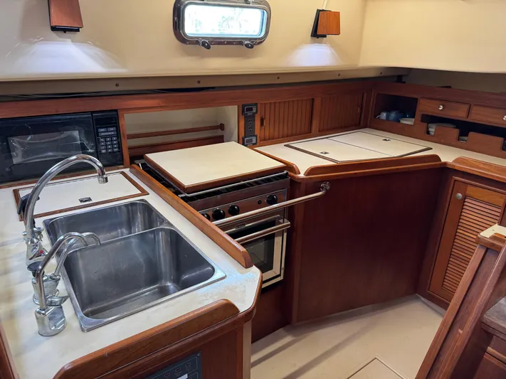 Otter II Yacht Photos Pics 1999 Island Packet 45 yacht kitchen with sink, stove, and wooden cabinetry.