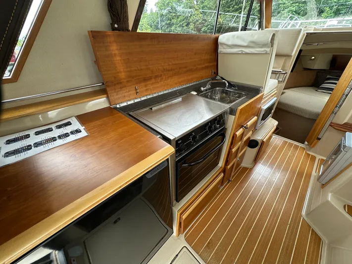  Yacht Photos Pics 2016 Cutwater CB boat interior with kitchen, stove, sink, and cozy sleeping area.