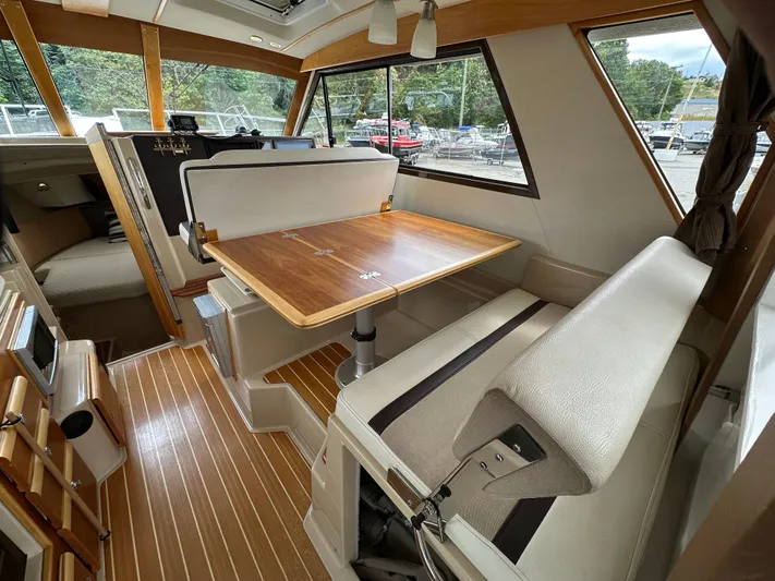  Yacht Photos Pics Interior of a 2016 Cutwater CB boat with wood table and cushioned seating.