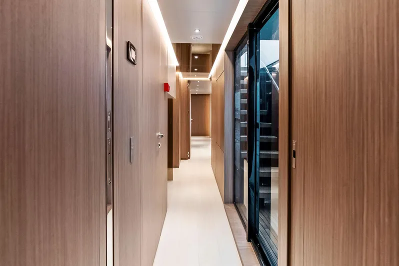 Ciao M Yacht Photos Pics Luxurious interior hallway of 2023 Custom Line 106' yacht, featuring sleek wood paneling.