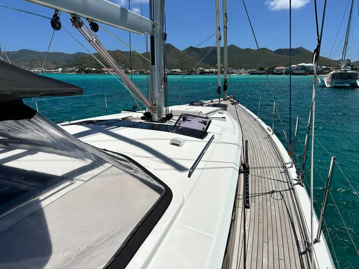  Yacht Photos Pics 2019 Beneteau Oceanis Yacht 62 sailing in turquoise waters with scenic mountain backdrop.