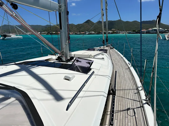  Yacht Photos Pics 2019 Beneteau Oceanis Yacht 62 sailing on turquoise waters with mountainous backdrop.