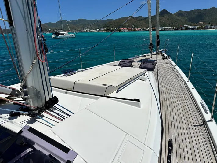  Yacht Photos Pics 2019 Beneteau Oceanis Yacht 62 sailing on turquoise waters near a coastal landscape.