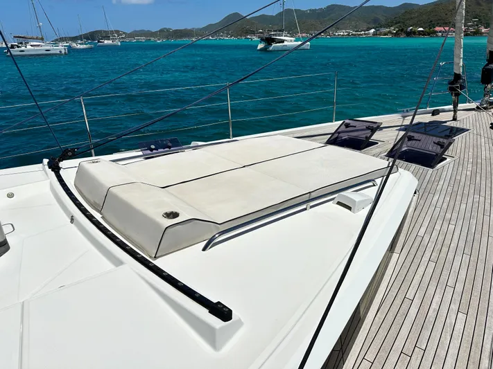  Yacht Photos Pics 2019 Beneteau Oceanis Yacht 62 deck with sun loungers, overlooking turquoise waters and distant hills.