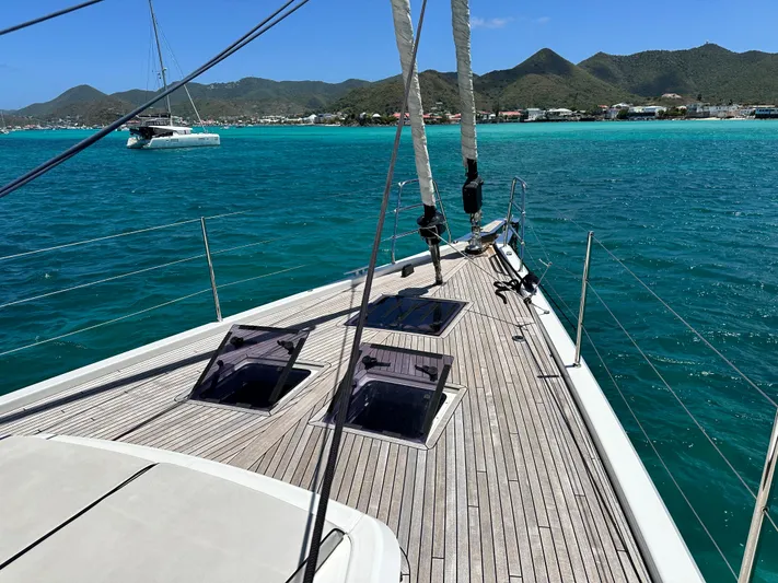  Yacht Photos Pics 2019 Beneteau Oceanis Yacht 62 sailing in turquoise waters with scenic mountain backdrop.
