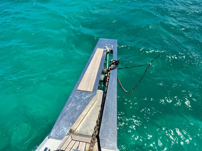  Yacht Photos Pics Bow of 2019 Beneteau Oceanis Yacht 62 with anchor chain over turquoise water.