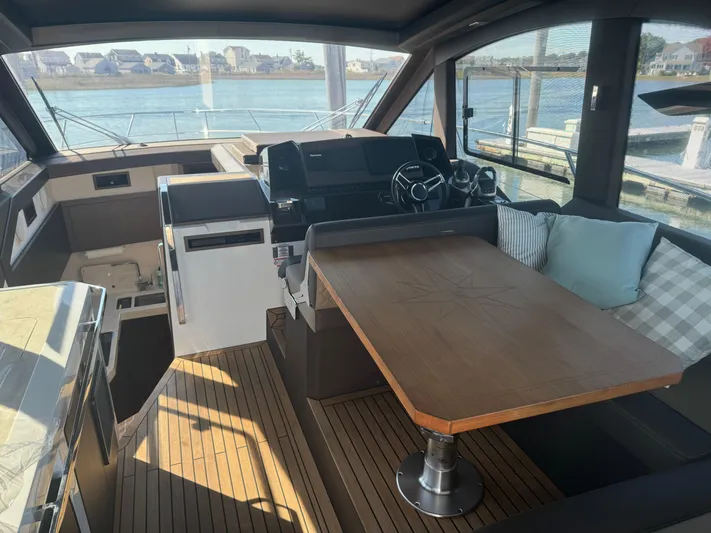  Yacht Photos Pics Interior of 2021 Galeon 425 HTS yacht with helm, seating, and wooden table.