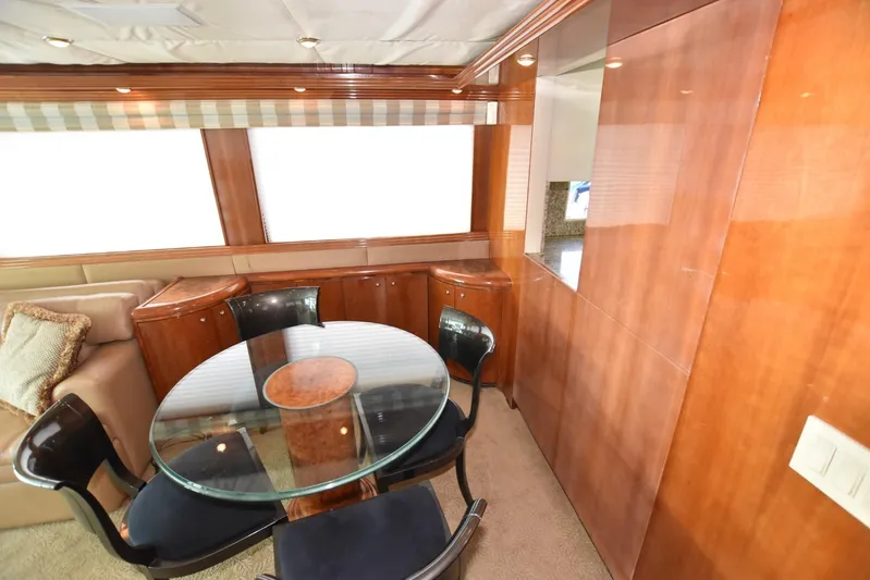 Big Hatt Yacht Photos Pics Luxurious interior of 1998 Hatteras 74 Sport Deck yacht with glass dining table and wooden cabinetry.