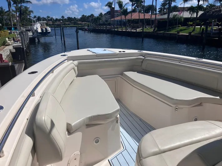  Yacht Photos Pics 2018 Grady-White Canyon 336 boat interior with cushioned seating, docked by a scenic waterfront.