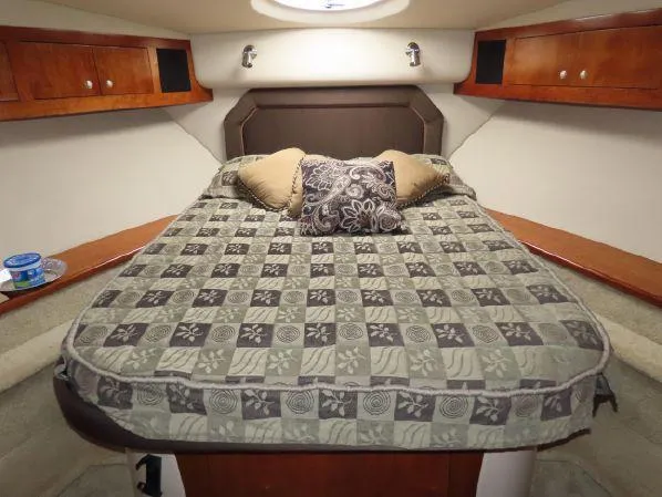 Gemini Yacht Photos Pics Luxurious 2004 Cruisers Yachts 405 Express Motoryacht bedroom with patterned bedding and wooden cabinets.