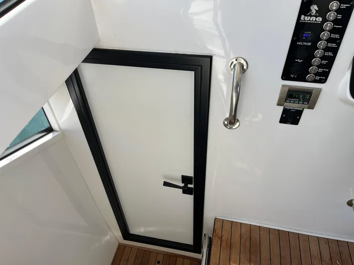  Yacht Photos Pics 2024 Tuna catamaran interior with sleek door, control panel, and wooden flooring.