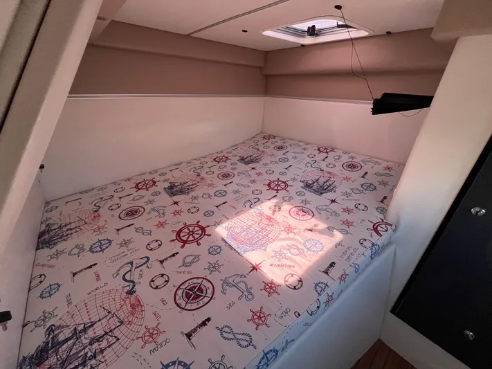  Yacht Photos Pics 2024 Tuna catamaran cabin with nautical-themed bedding and overhead hatch.