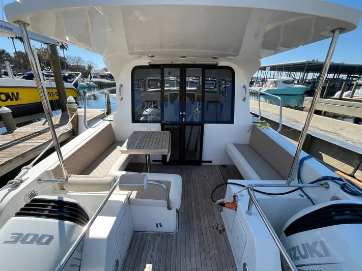  Yacht Photos Pics 2024 Tuna catamaran with spacious deck, seating, and dual Suzuki engines at a marina.