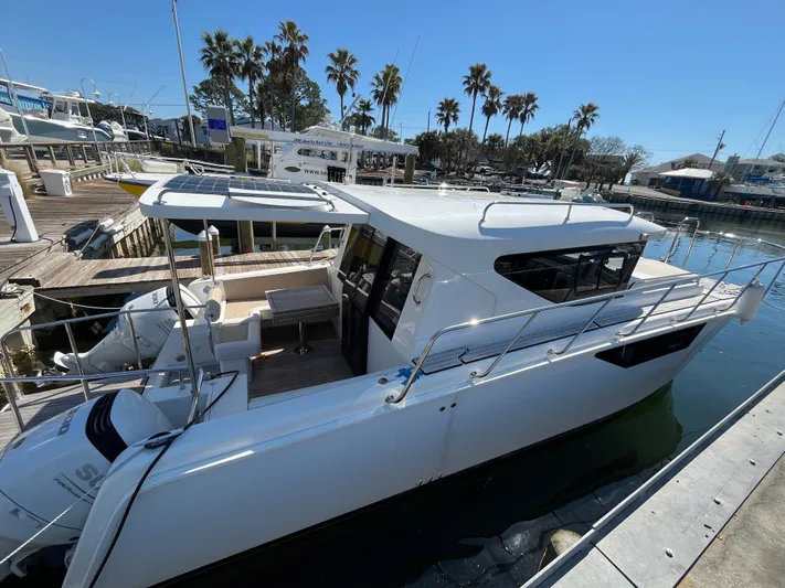  Yacht Photos Pics 2024 Tuna catamaran docked at marina, surrounded by palm trees and clear blue sky.