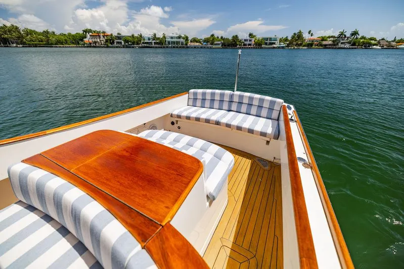  Yacht Photos Pics 2004 Hinckley Talaria 29 R boat with striped seating, wooden deck, and scenic waterfront view.