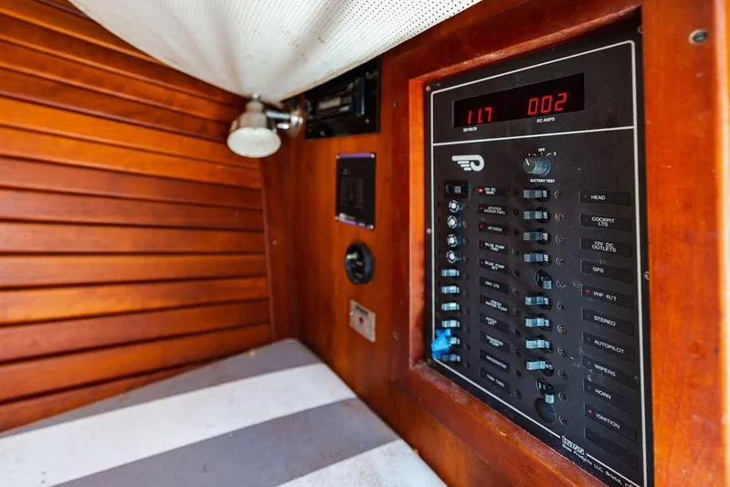  Yacht Photos Pics Electrical panel inside 2004 Hinckley Talaria 29 R boat, featuring wooden interior and striped cushion.