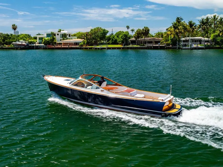  Yacht Photos Pics 2004 Hinckley Talaria 29 R cruising on a scenic waterway with lush greenery.