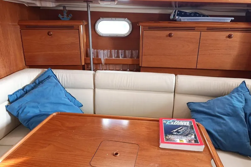  Yacht Photos Pics Cozy interior of 2004 Jeanneau Sun Odyssey 43 with wooden cabinetry and blue cushions.