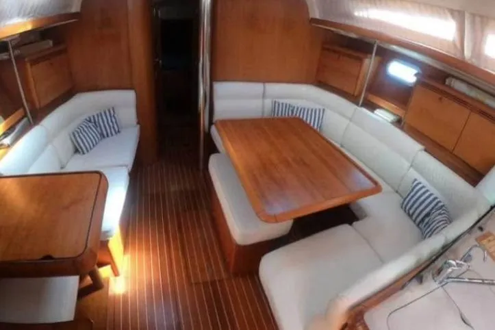  Yacht Photos Pics Interior of 2004 Jeanneau Sun Odyssey 43 sailboat with wooden furnishings and white seating.