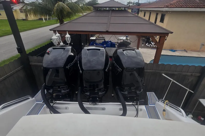  Yacht Photos Pics Triple outboard motors on a 2016 Extreme Boats model, parked near a poolside patio.