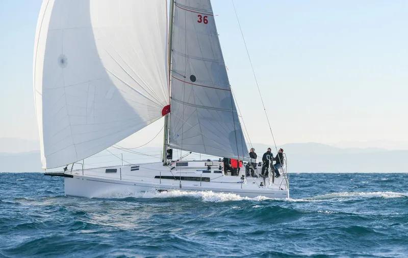  Yacht Photos Pics 2025 Beneteau First 36 sailboat navigating ocean waters with crew onboard.