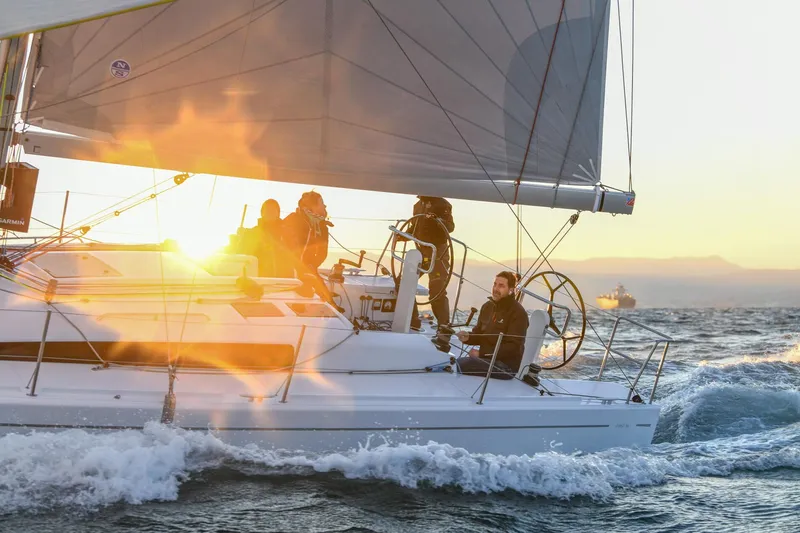  Yacht Photos Pics 2025 Beneteau First 36 sailing at sunset with crew on deck.