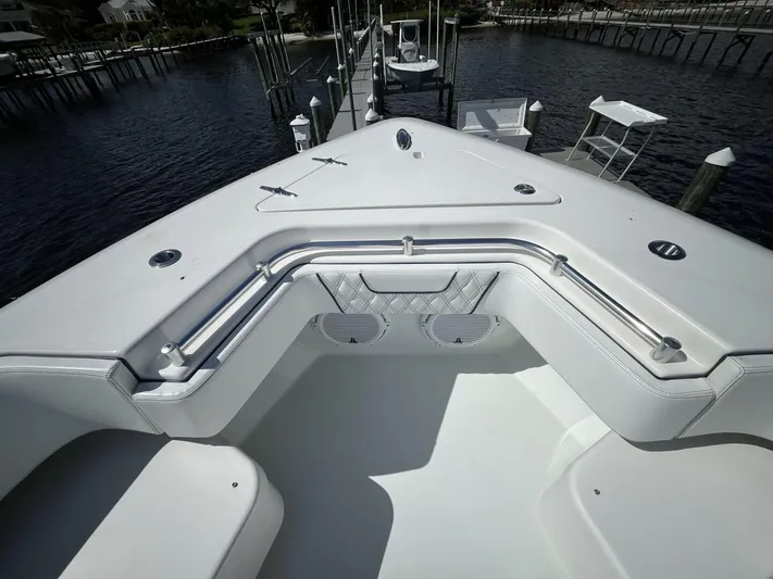  Yacht Photos Pics 2021 Contender 44ST boat bow with seating and railings, docked by the water.