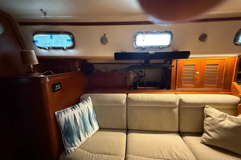 Windragon Yacht Photos Pics Cozy interior of 1995 Island Packet 37 sailboat with cushioned seating and wooden cabinetry.