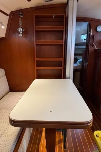 Windragon Yacht Photos Pics Interior of a 1995 Island Packet 37 sailboat with wooden shelves and a dining table.