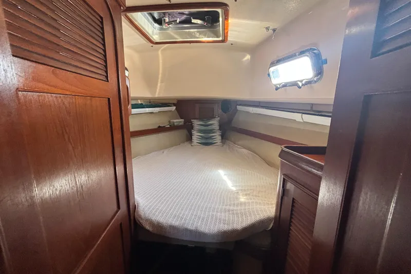 Windragon Yacht Photos Pics Cozy cabin interior of 1995 Island Packet 37 sailboat with wooden finishes and a bed.