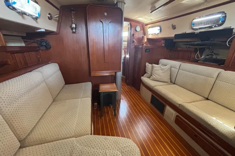 Windragon Yacht Photos Pics Interior of a 1995 Island Packet 37 sailboat with wooden finishes and cushioned seating.