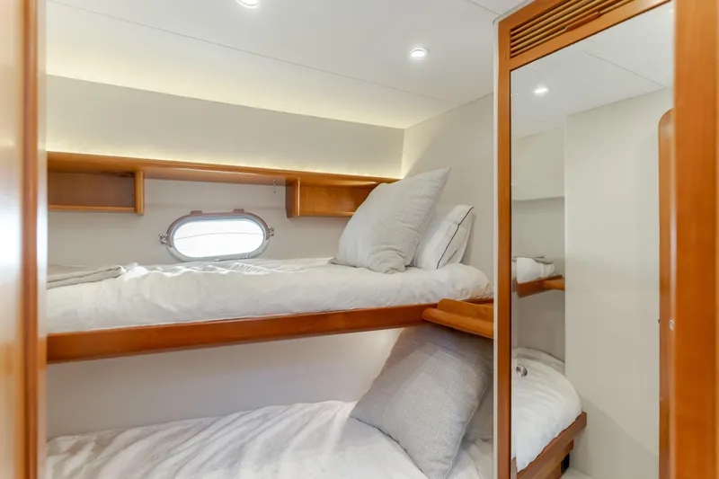  Yacht Photos Pics Cozy bunk beds in 2006 West Bay 64 yacht cabin with wooden accents and porthole window.