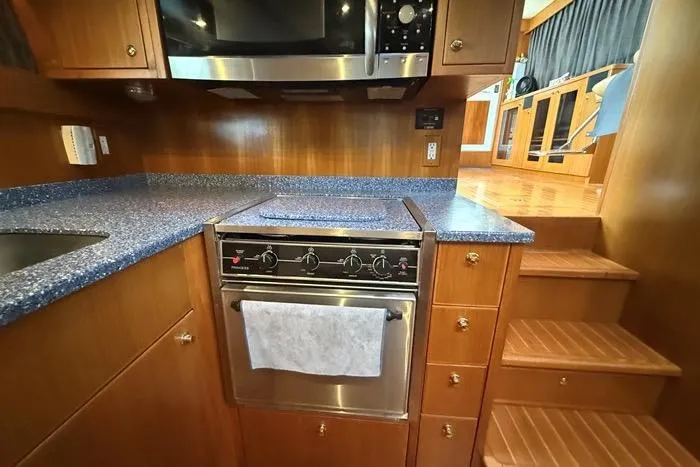  Yacht Photos Pics 2007 Island Pilot 395 yacht kitchen with stove, microwave, and wooden cabinetry.