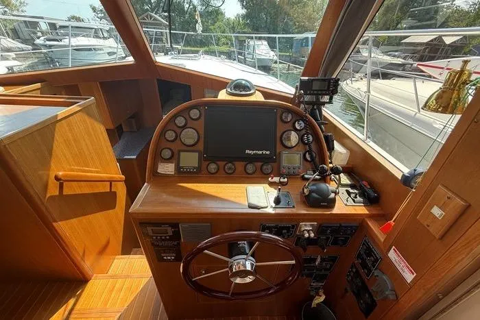  Yacht Photos Pics 2007 Island Pilot 395 helm with Raymarine electronics and wooden steering wheel in a marina setting.