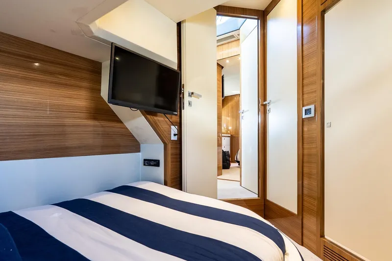 Balliamo Yacht Photos Pics Luxurious 2011 Uniesse 55S yacht cabin with striped bedding and wall-mounted TV.