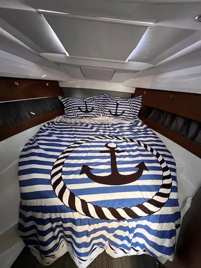  Yacht Photos Pics Cozy cabin interior of 2020 Jeanneau NC 895 with nautical-themed bedding.