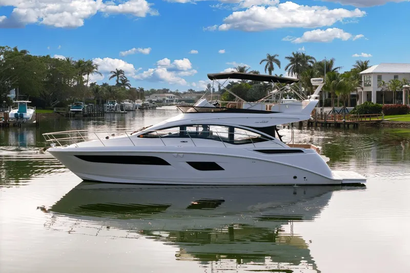 Our Journey Yacht Photos Pics 2017 Sea Ray 400 Fly yacht on a serene waterway with palm trees and blue sky.