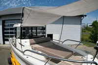 2021 Nimbus C8 boat with sunshade, docked near a modern building.