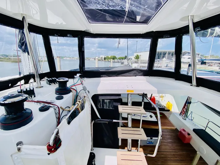 No Schedule Yacht Photos Pics Interior view of 2019 Lagoon 42 Owners Version catamaran, featuring helm station and marina backdrop.