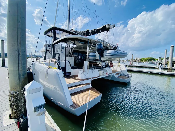 No Schedule Yacht Photos Pics 2019 Lagoon 42 Owners Version catamaran docked at marina under blue sky.