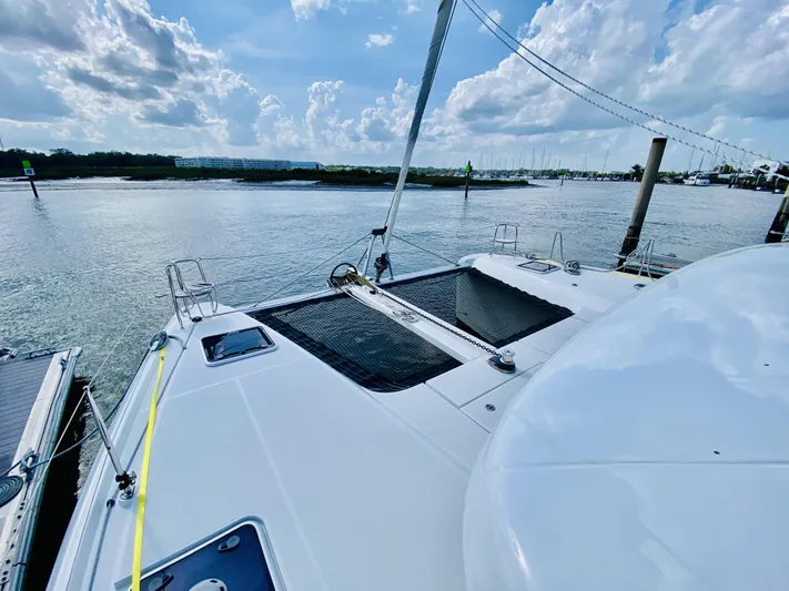 No Schedule Yacht Photos Pics 2019 Lagoon 42 Owners Version catamaran docked by a scenic waterfront under a cloudy sky.