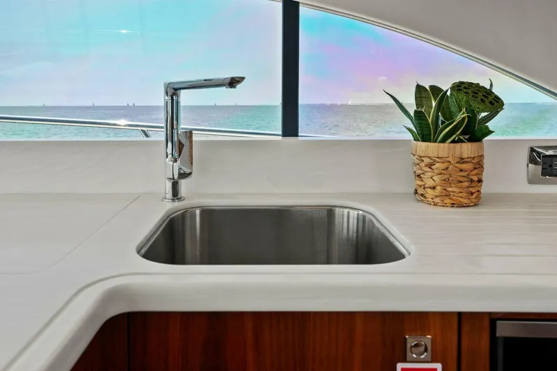 Gia Yacht Photos Pics Modern yacht kitchen sink with ocean view, featuring a potted plant. Riviera 5400 Sport Yacht 2021.