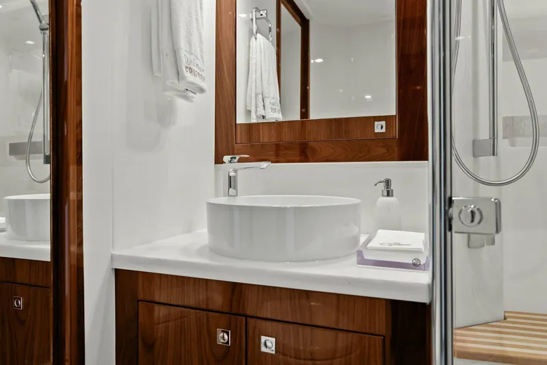 Gia Yacht Photos Pics Luxurious bathroom in 2021 Riviera 5400 Sport Yacht with modern sink and wooden cabinetry.