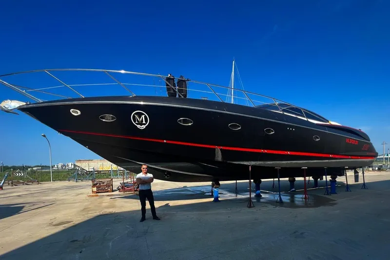  Yacht Photos Pics Sunseeker Predator 58 yacht from 2000 on dry dock, with a person standing nearby.