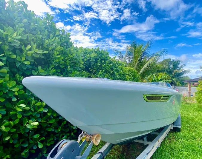  Yacht Photos Pics 2008 Porsche Fearless 28 boat on trailer, surrounded by lush greenery and blue sky.